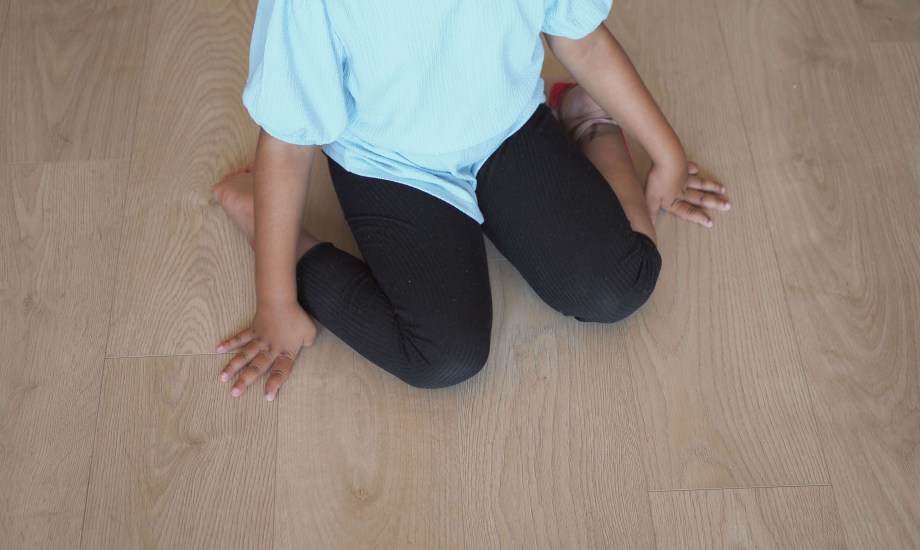 طفلة تجلس على شكل حرف W على الأرض